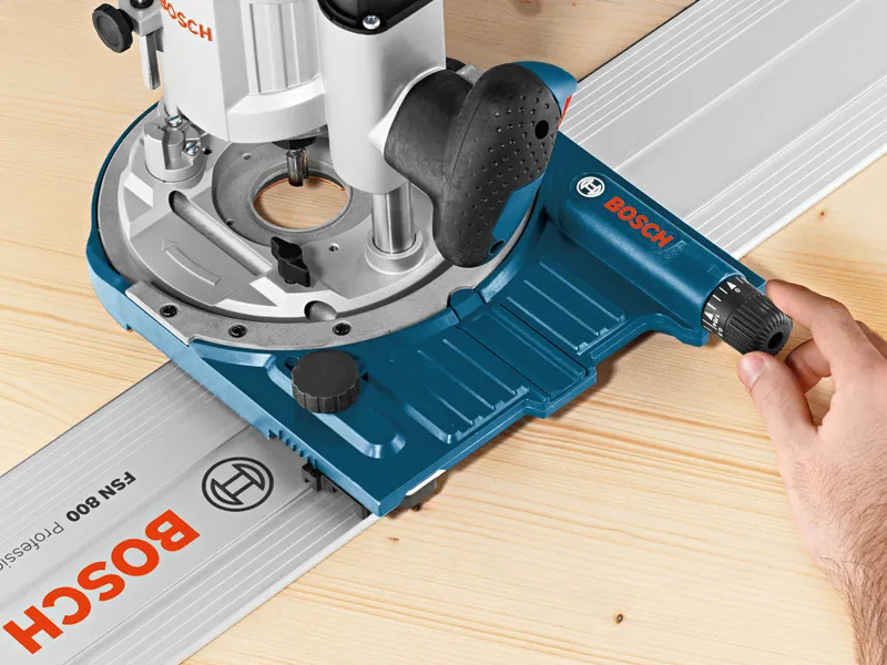 A person adjusts a system accessory track guide on a wooden surface.