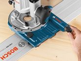 A person adjusts a system accessory track guide on a wooden surface.