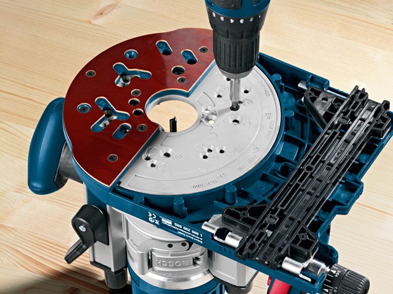 Drill driving a screw into a system accessory base plate on a router tool.