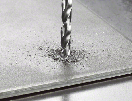 Metal drill bits HSS-G, DIN 338 Drill bit making a hole in a metal sheet with metal shavings around the hole.
