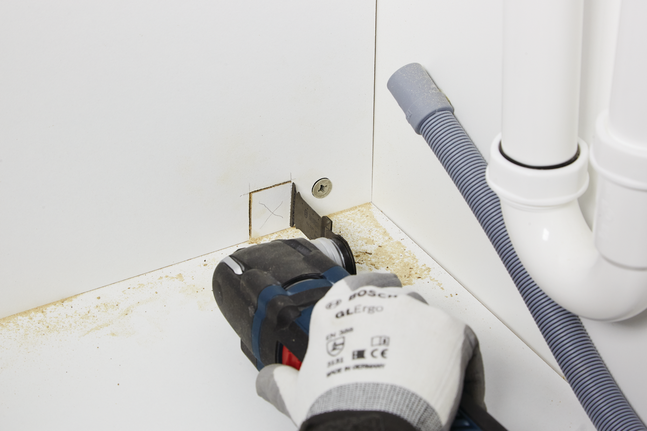 HCS plunge cut saw blade AIZ 32 BSPC Hard Wood Worker wearing safety equipment cuts a square opening in a cabinet with a power tool.