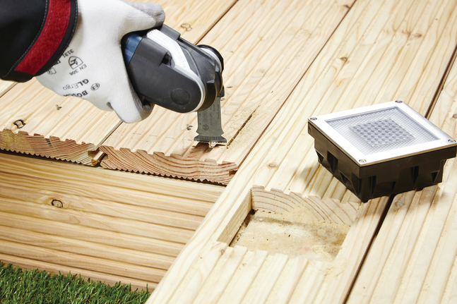 HCS plunge cut saw blade AIZ 32 BSPC Hard Wood Worker wearing safety equipment cuts a groove in a wooden deck using a multi-tool.