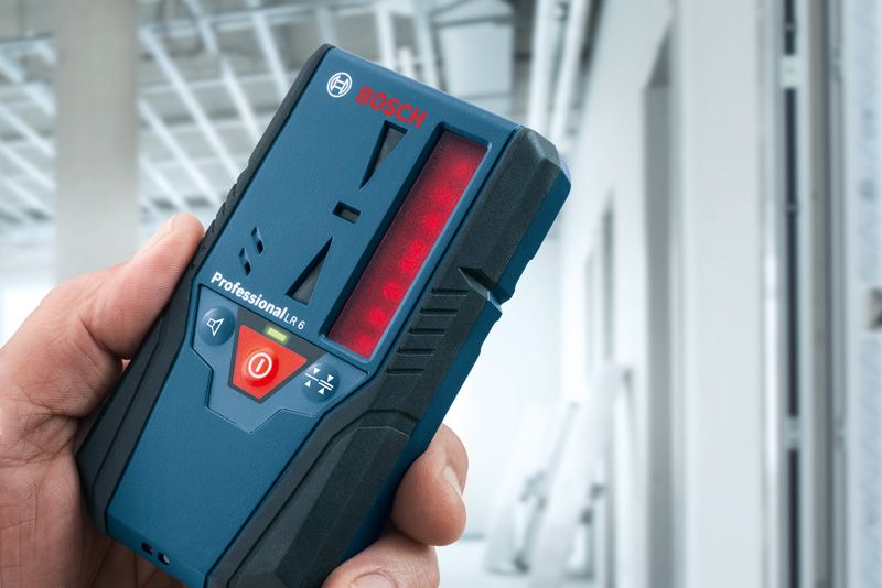 Person holding a laser receiver in a building under construction.