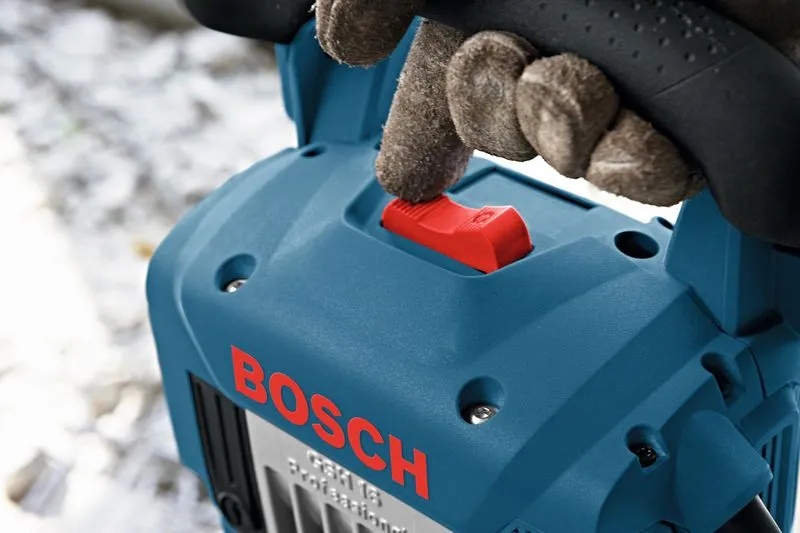 Person wearing safety equipment presses a red switch on a blue power tool.