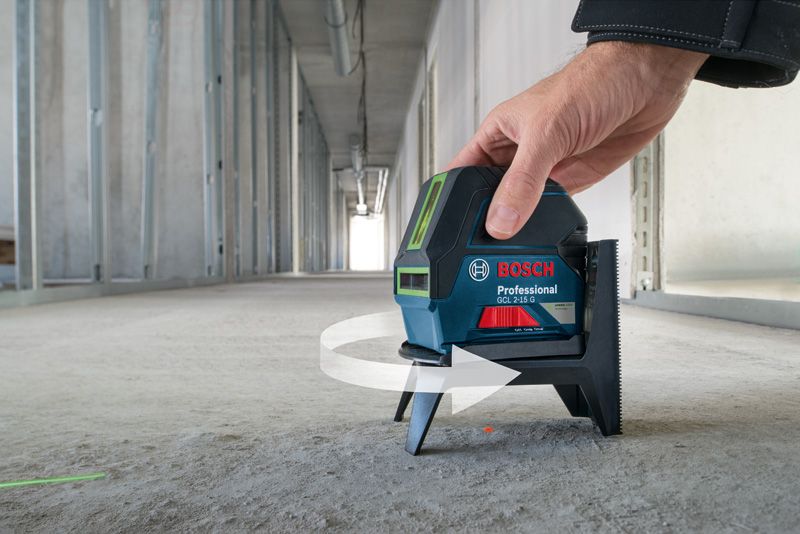 GCL 2-15 G A person adjusts a laser leveling tool on a concrete floor in an unfinished hallway.