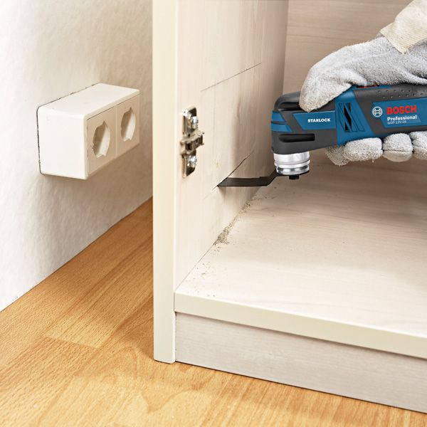 GOP 12V-28 A person wearing safety equipment uses a cordless multi-cutter to cut wood inside a cabinet.