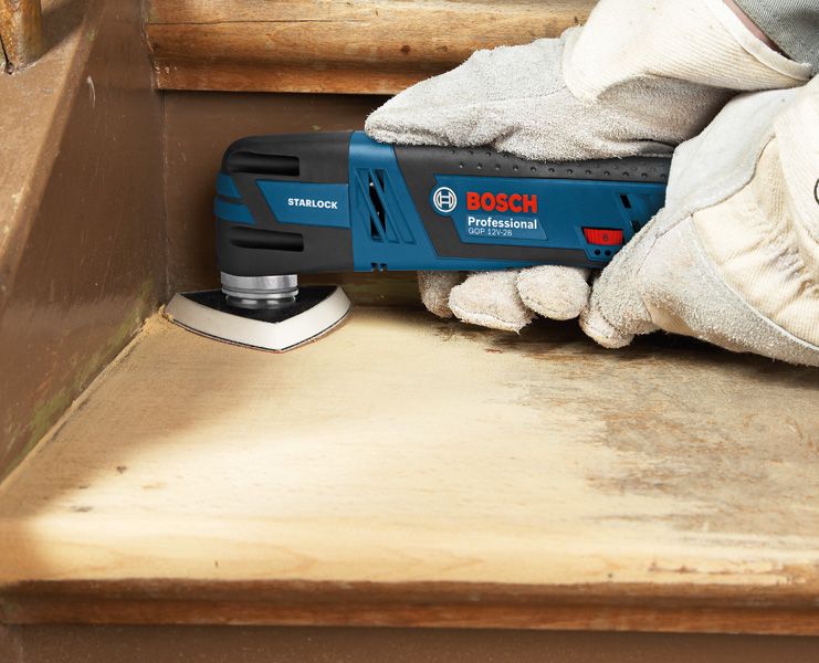 GOP 12V-28 A person wearing safety equipment sands a wooden stair with a cordless multi-cutter.