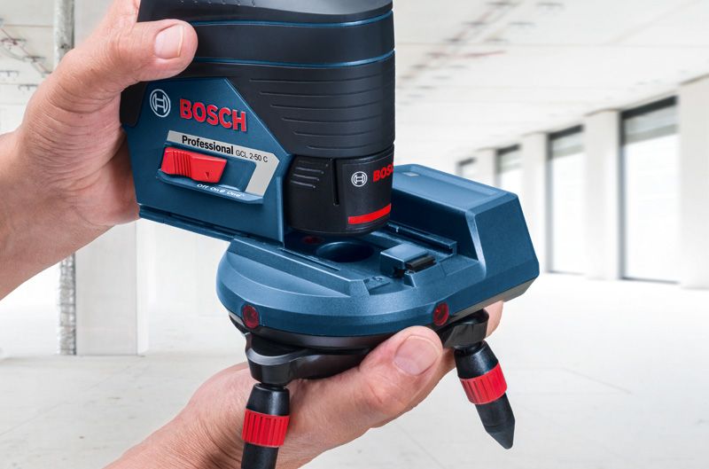 RM 3 Person adjusts a laser leveling tool accessory in a bright, unfinished room.