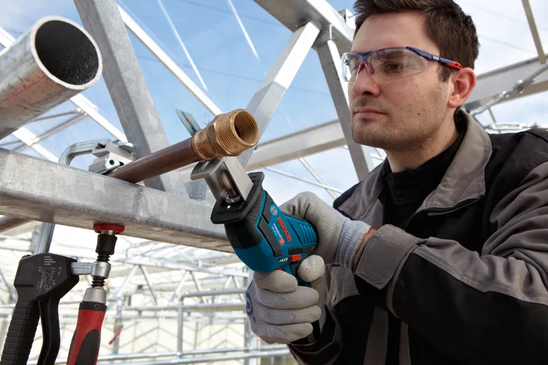 GSA 12V-Li A person wearing safety equipment uses a cordless reciprocating saw to cut a metal pipe.