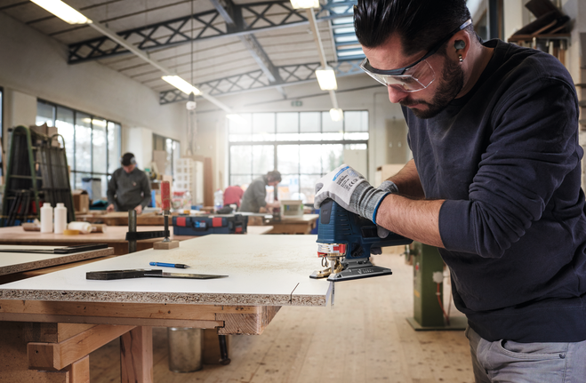 Jigsaw blade T 101 AO Person wearing safety equipment uses a jigsaw to cut particle board in a workshop.