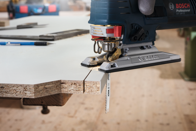 Jigsaw blade T 101 AO Gloved worker uses a jigsaw to cut a precise line through laminated wood.