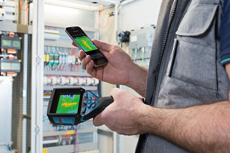 GTC 400 C Person uses a thermo camera and smartphone to check heat patterns in an electrical panel.