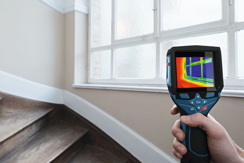 GTC 400 C Person uses thermal camera to scan temperature changes near a window.
