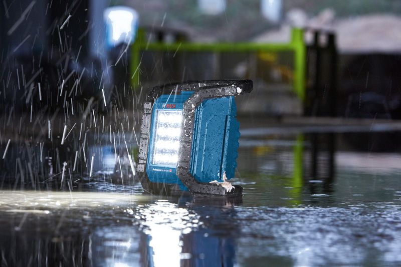 Work light operating on a wet floor during heavy rain at a construction site.