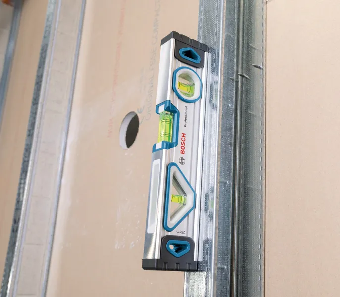 Hand Tool Mixed Set 13pc Spirit level measuring vertical alignment on a metal stud and drywall panel.