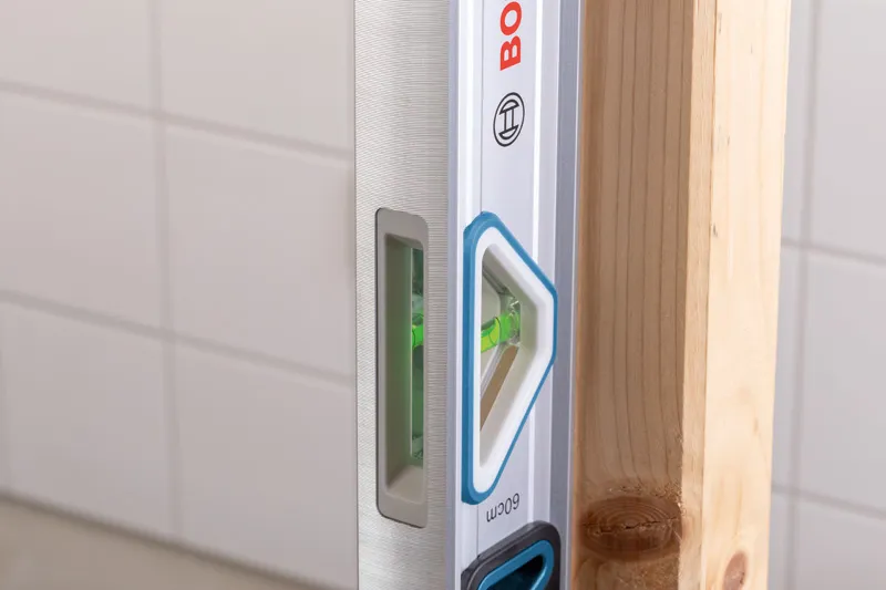 Level 60 cm Laser leveling tool checking vertical alignment of a wooden beam.