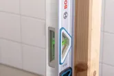 Laser leveling tool checking vertical alignment of a wooden beam.