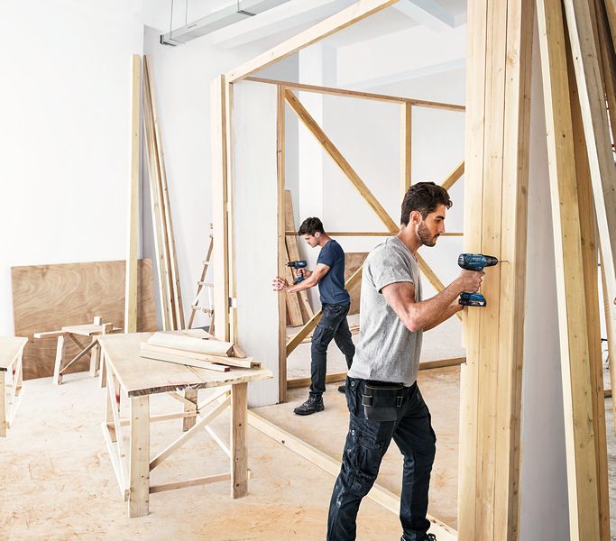 Two men building wooden wall.