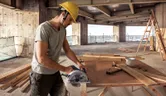 Worker sawing wooden board.