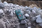 A laser measure resting on a pile of rocks at a construction site.