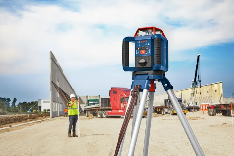 GRL 350 HV Laser leveling tool on tripod at a construction site, person wearing safety equipment in background.