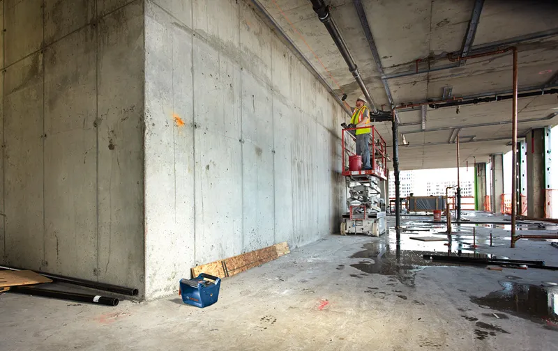 GRL 350 HV A person wearing safety equipment uses a laser leveling tool on a concrete wall.