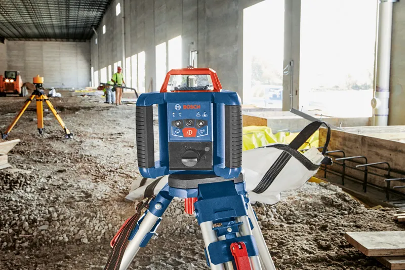 GRL 350 HV Laser leveling tool set on a tripod at a construction site, person wearing safety equipment in background.