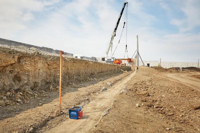 GRL 350 HV Laser leveling tool set up on a construction site with cranes and earthmoving in the background.