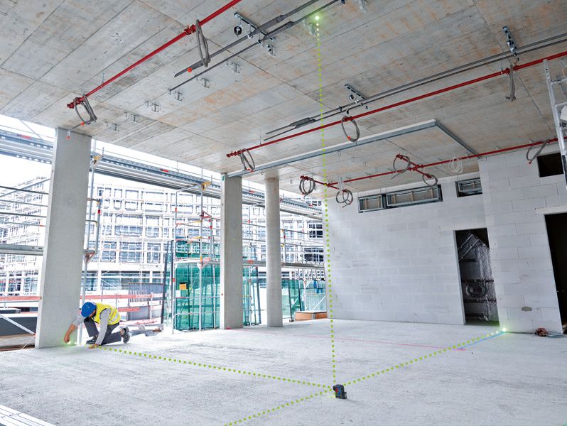 Person wearing safety equipment uses a laser leveling tool to align points in a construction area.