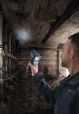 A person scans a damp ceiling in a basement with a thermo detector.