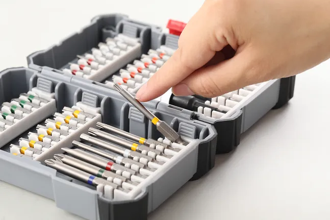 Person selects a screwdriver bit from an organized toolkit.