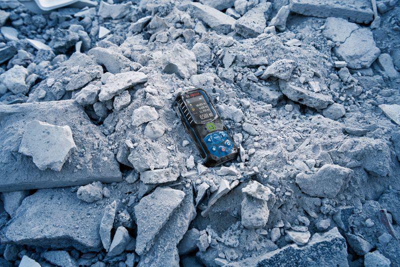 Laser measure resting on a pile of broken concrete debris.