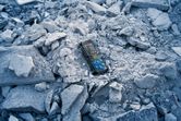 Laser measure device lying on a pile of broken concrete rubble.