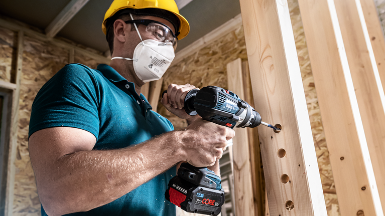 EXPERT Self Cut Speed Spade Drill Bit Set 13/16/19/20/22/25 mm 6-pc Person wearing safety equipment drills holes in wooden beams.
