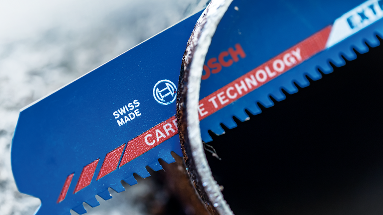 EXPERT Thick Tough Metal S1155CHC Reciprocating Saw Blade 1-pc Close-up of a blue saw blade with carbide teeth cutting through a metal pipe.