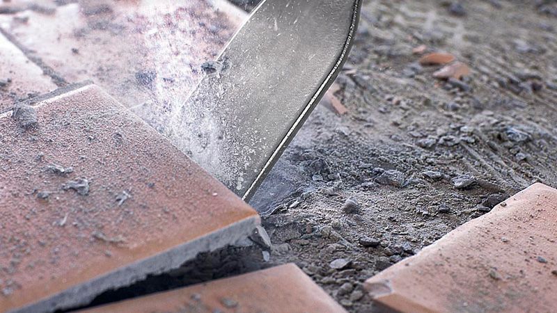 GSH 3 Tile chisel breaking ceramic tiles on a dusty floor.