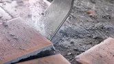 Tile chisel breaking ceramic tiles on a dusty floor.