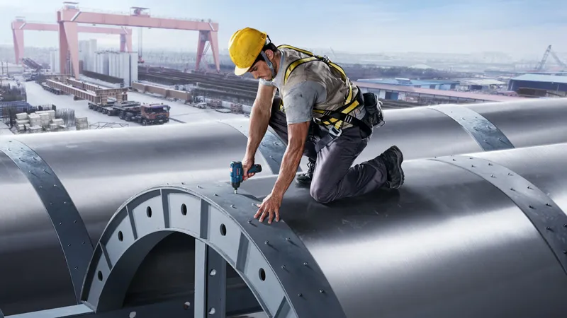 GSB 120-Li + GDR 120-Li A person wearing safety equipment fastens bolts on a large metal structure using a power tool.
