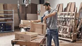 A person wearing safety equipment assembles a wooden drawer using a cordless combi drill.
