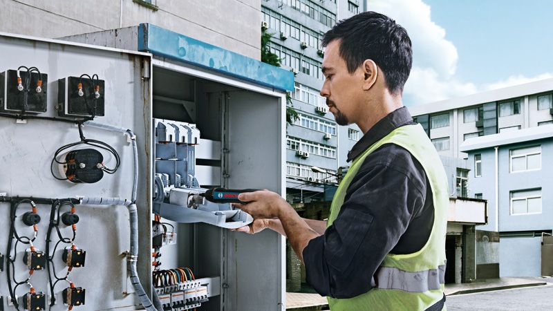 Bosch GO A person wearing safety equipment uses a cordless screwdriver on an electrical panel.