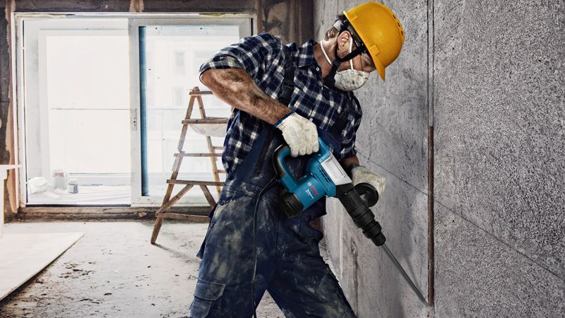 GSH 500 A person wearing safety equipment uses a demolition hammer to break a concrete wall.