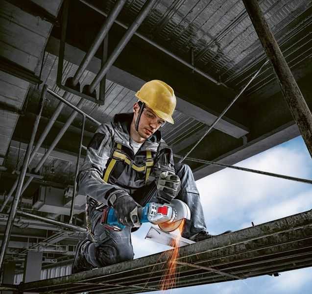 GWX 180-LI A person wearing safety equipment uses a cordless angle grinder to cut metal.