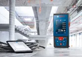 Laser measure and tablet displaying measurements on a concrete surface at a construction site.