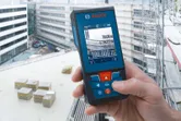A person uses a laser measure on a construction site balcony.
