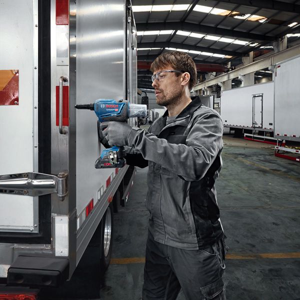 GRG 18V-16 C A person wearing safety equipment uses a cordless impact wrench on a truck door.