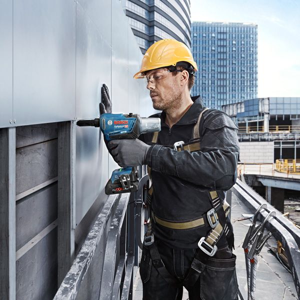 GRG 18V-16 C A person wearing safety equipment uses a power drill to fasten panels on a building exterior.