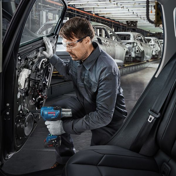 GRG 18V-16 C A person wearing safety equipment uses a power tool to assemble a car door in a factory.