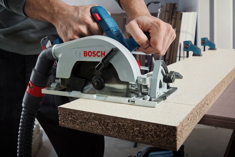 GKS 185-LI A person uses a cordless circular saw to cut particle board.