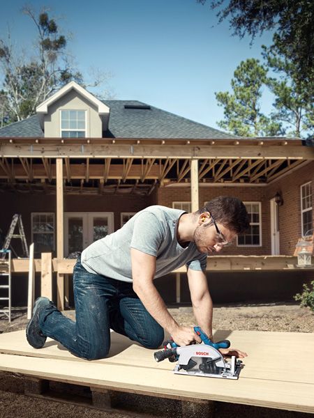 GKS 185-LI A person wearing safety equipment cuts wood on a construction site with a cordless circular saw.