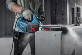 A person wearing safety equipment cuts an AAC block using an electric block cutter.